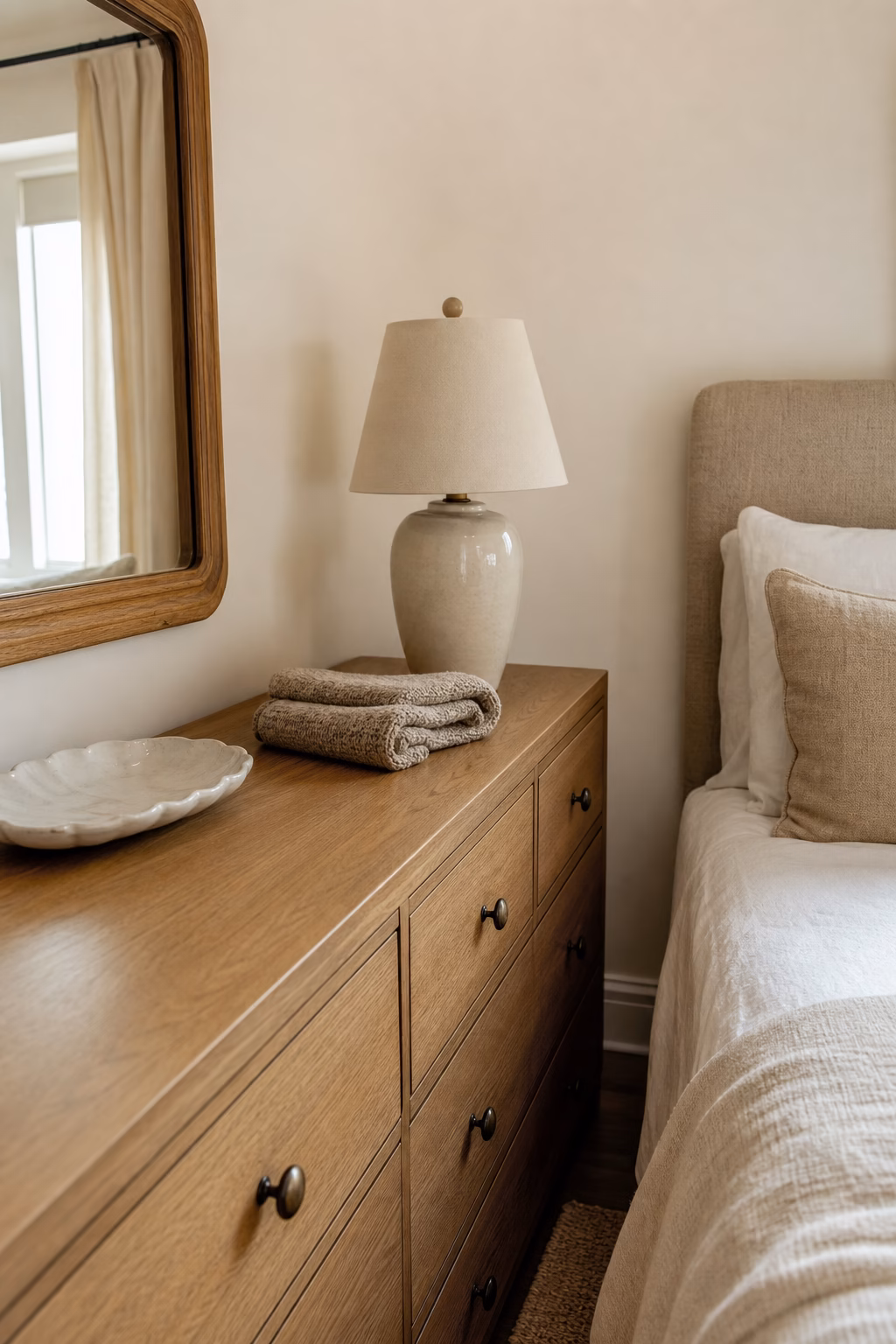 Small bedroom with edited dresser top, ceramic tray, simple lamp, and tidy bed