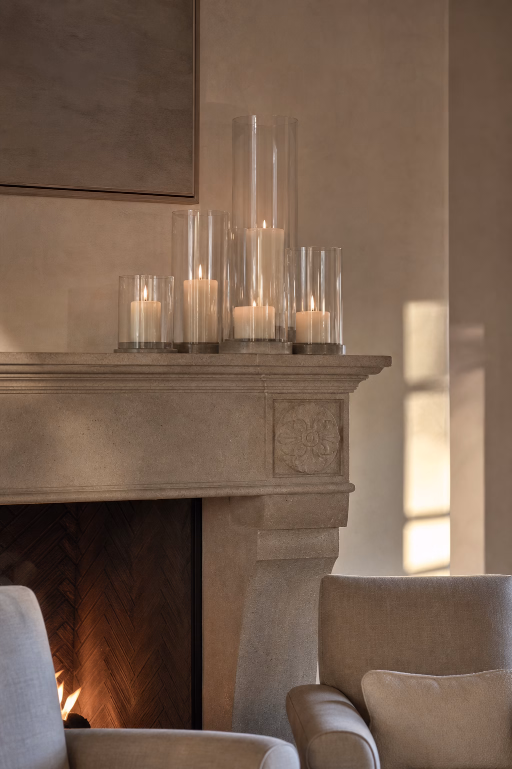 Clear glass hurricane candle holders on a refined stone mantel