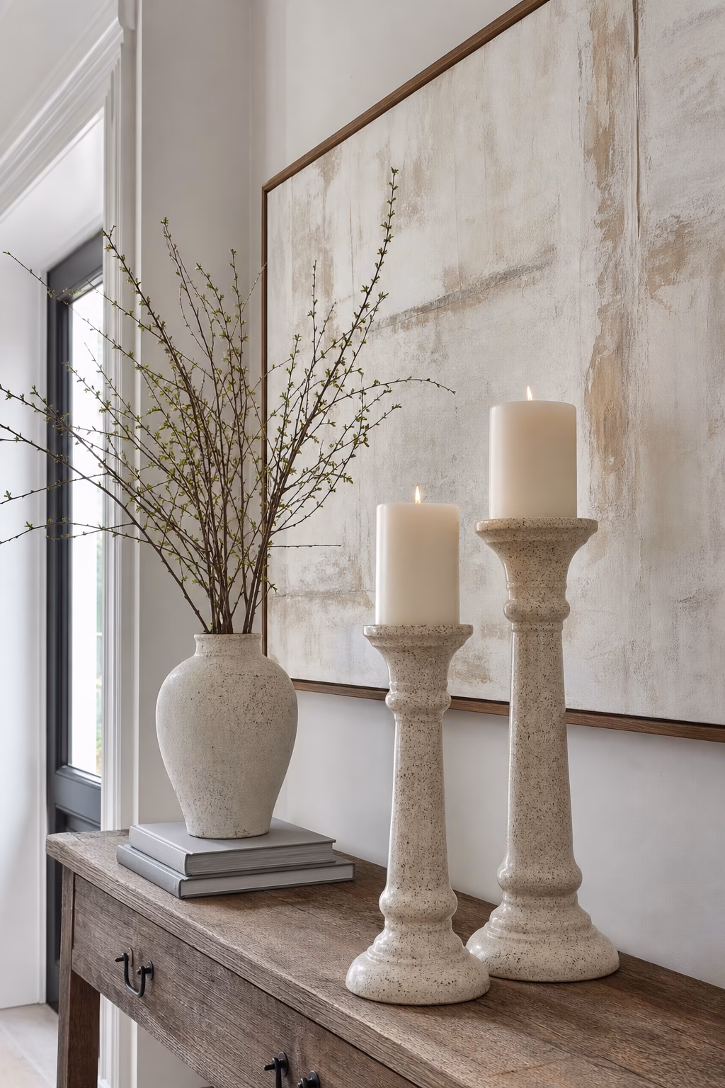 Tall speckled ceramic pillar candle stands on an elegant console