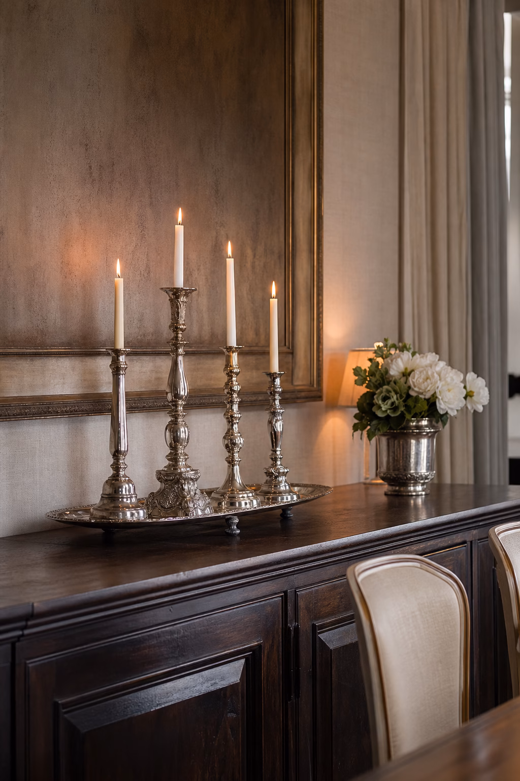 Patinated silver candlesticks styled on a refined dining sideboard