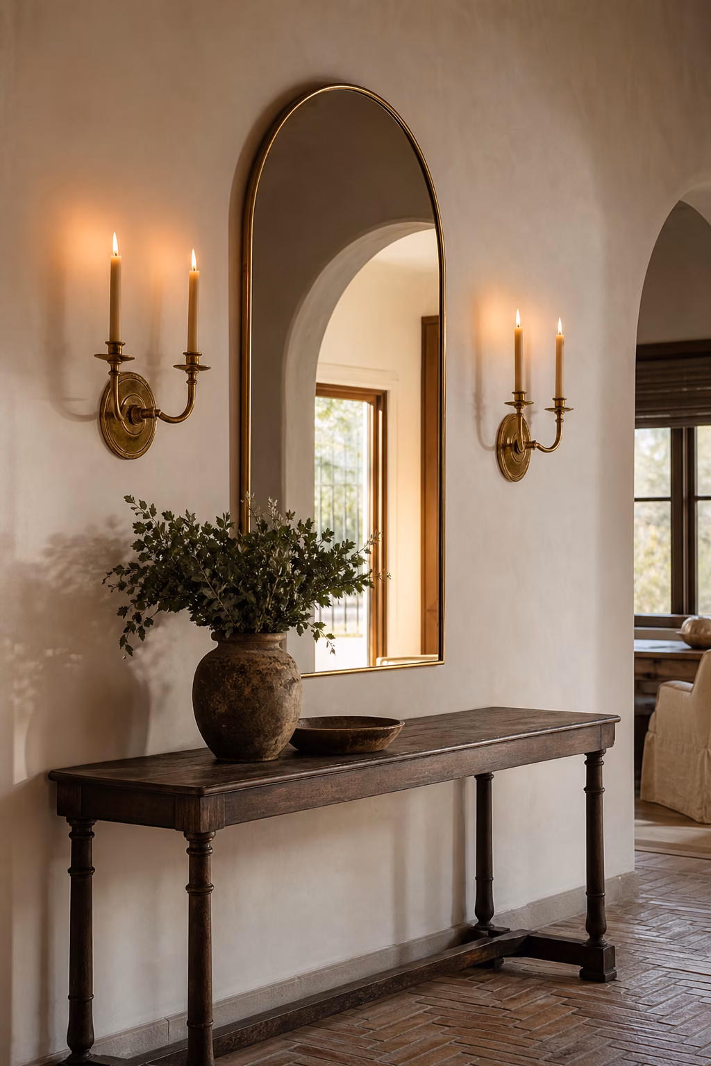 Brass wall-mounted candle sconces flanking an arched hallway mirror