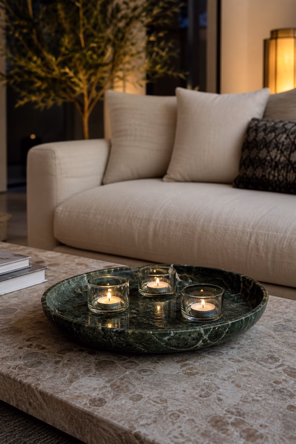 Low green marble tealight tray glowing on a stone coffee table