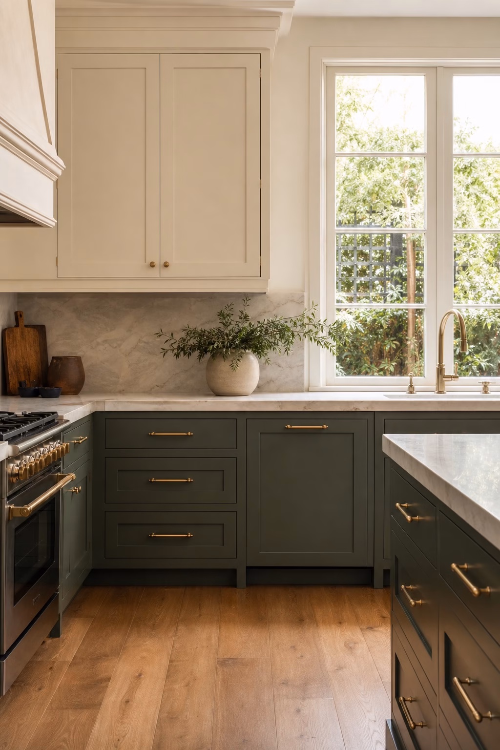 Kitchen with deep green lower cabinets, light uppers, stone counter, brass hardware, and wood floor