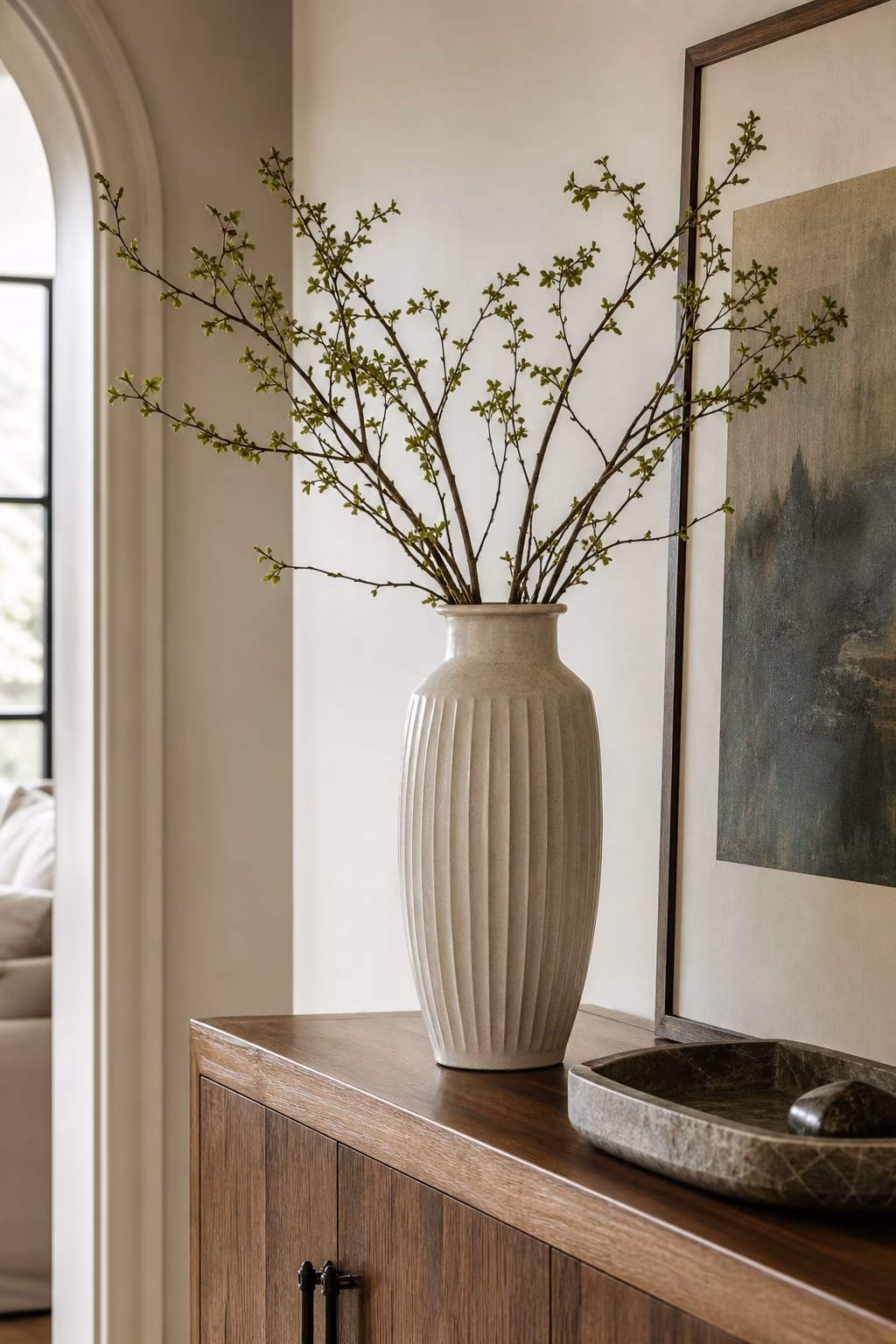 Tall ceramic vase holding fresh branches on a living room console