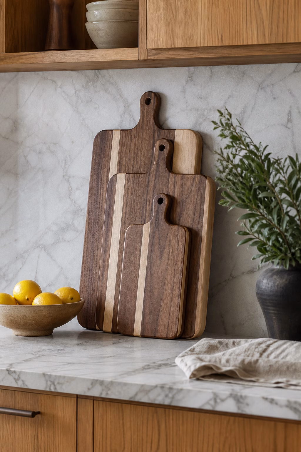 Layered walnut and maple cutting boards leaning against a marble backsplash