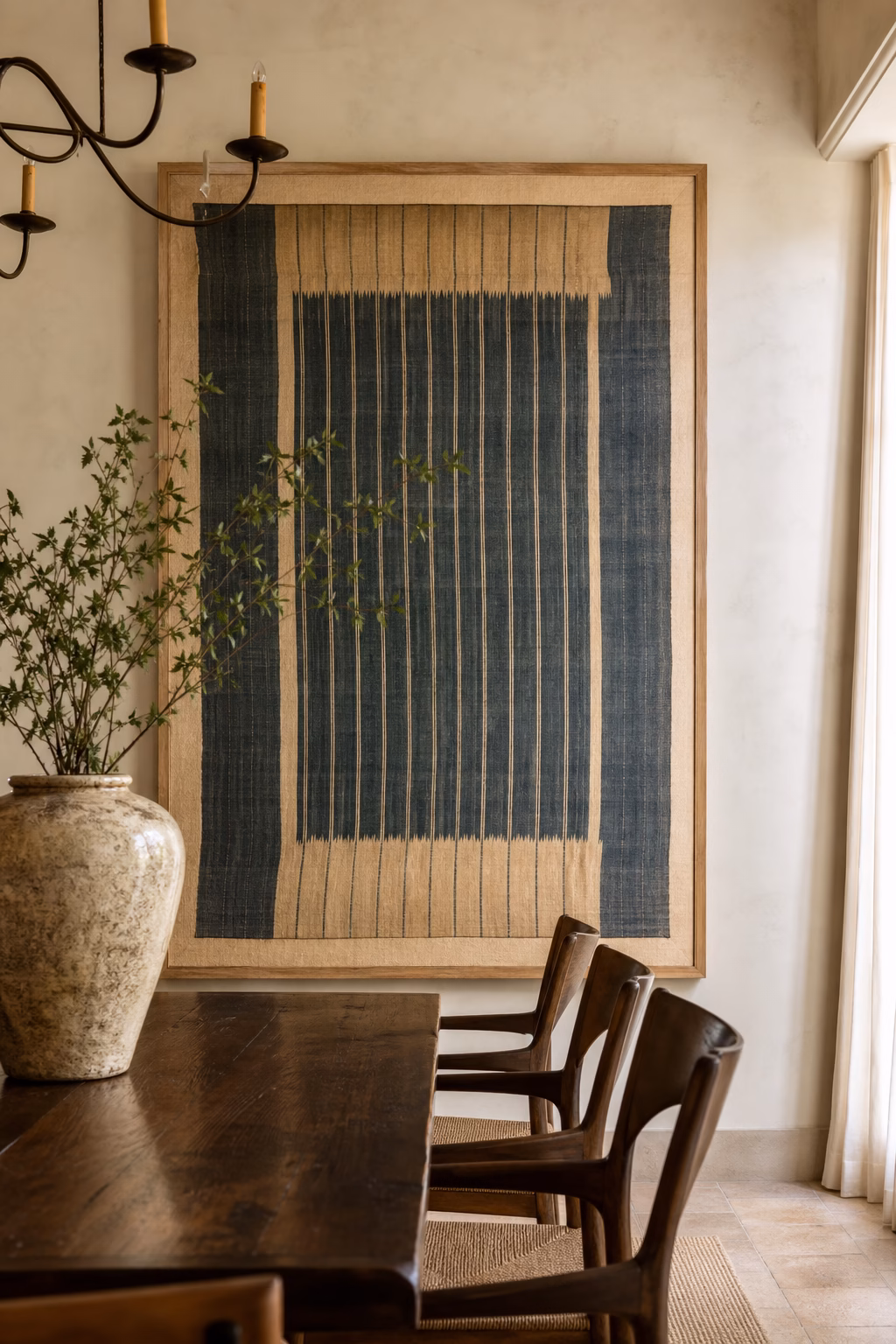 Round fiber wall hanging centered above a small breakfast table.