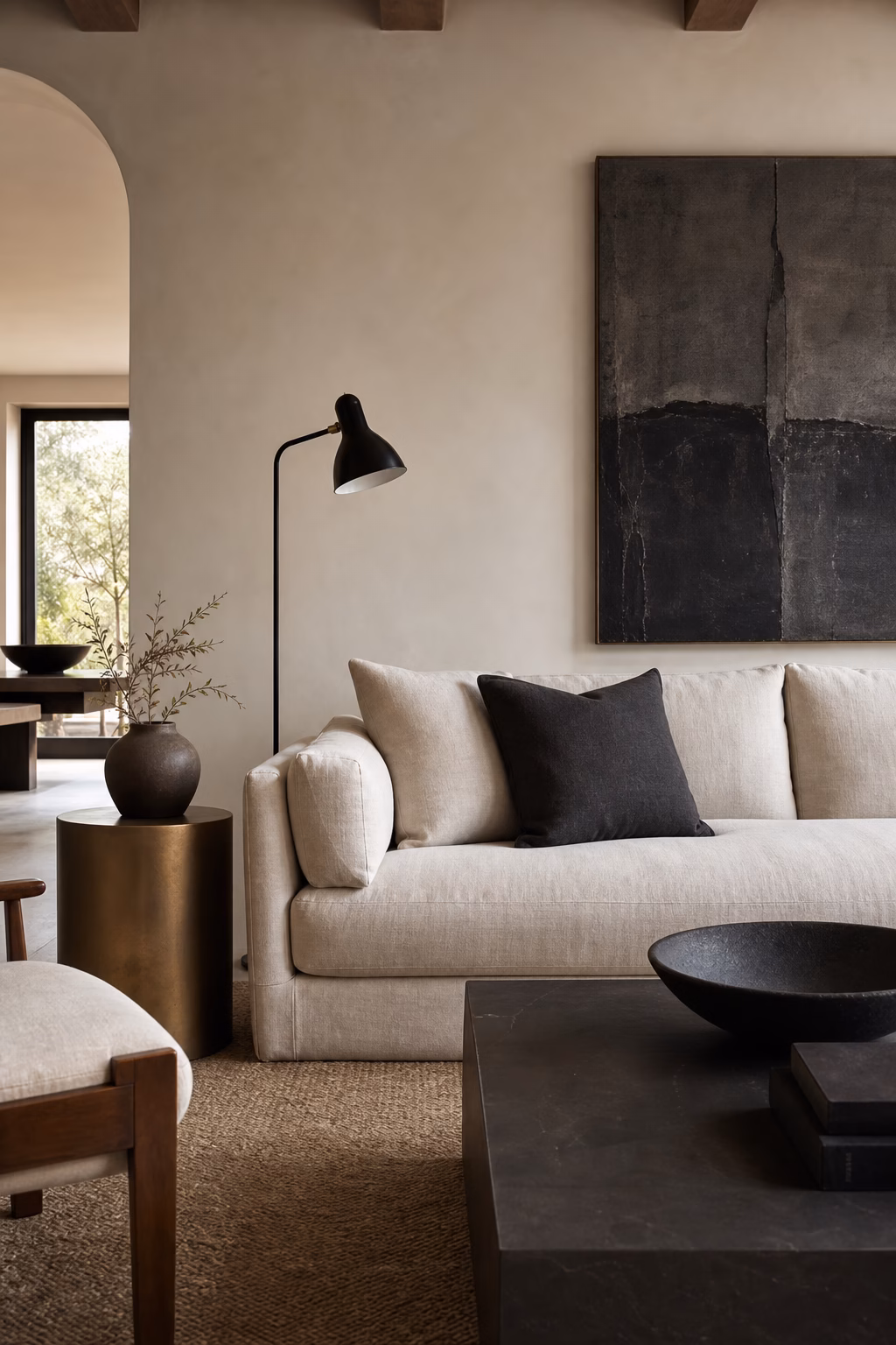 Neutral living room with black floor lamp charcoal art pale sofa and warm white walls