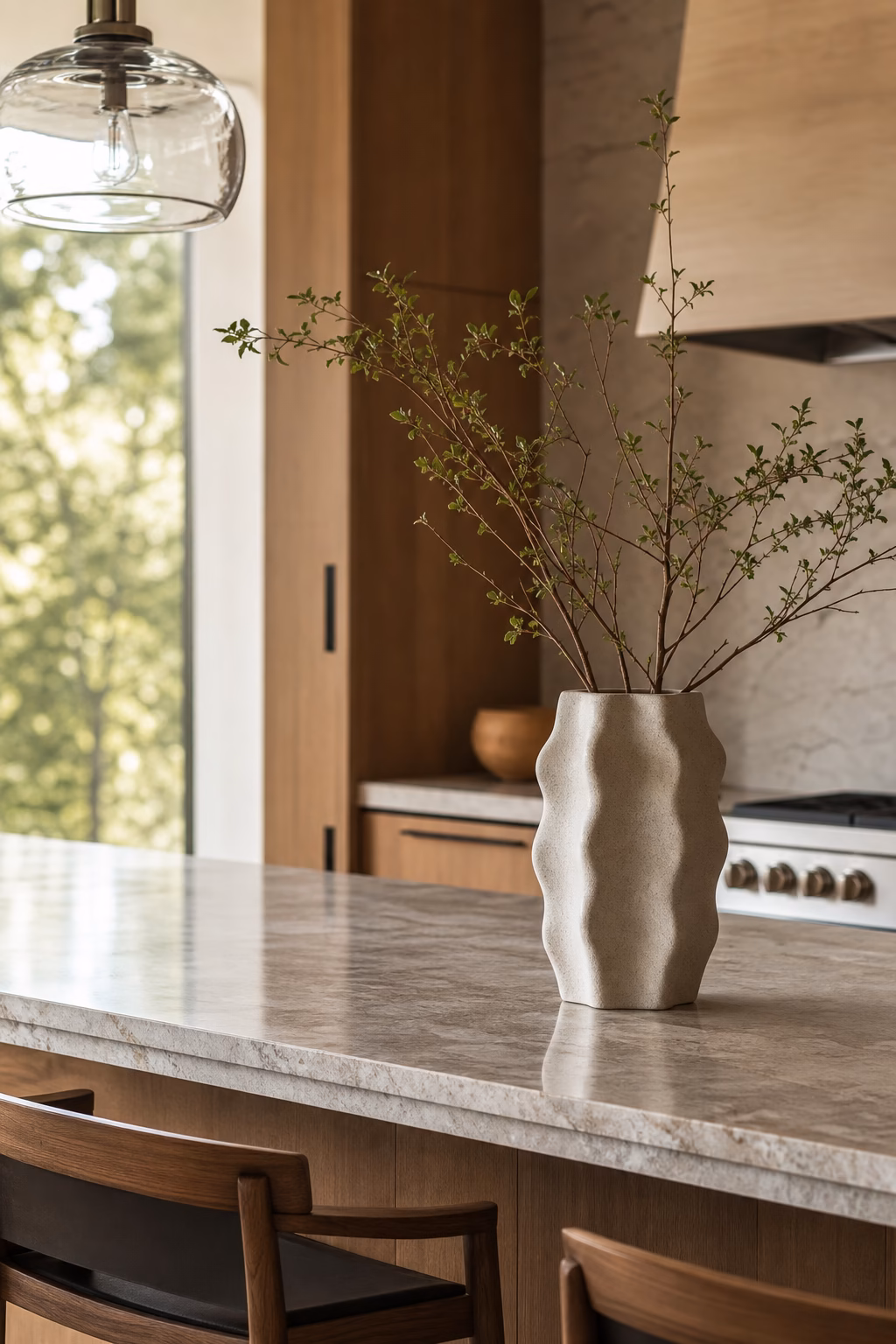 Single sculptural vessel adding height to a sleek kitchen island