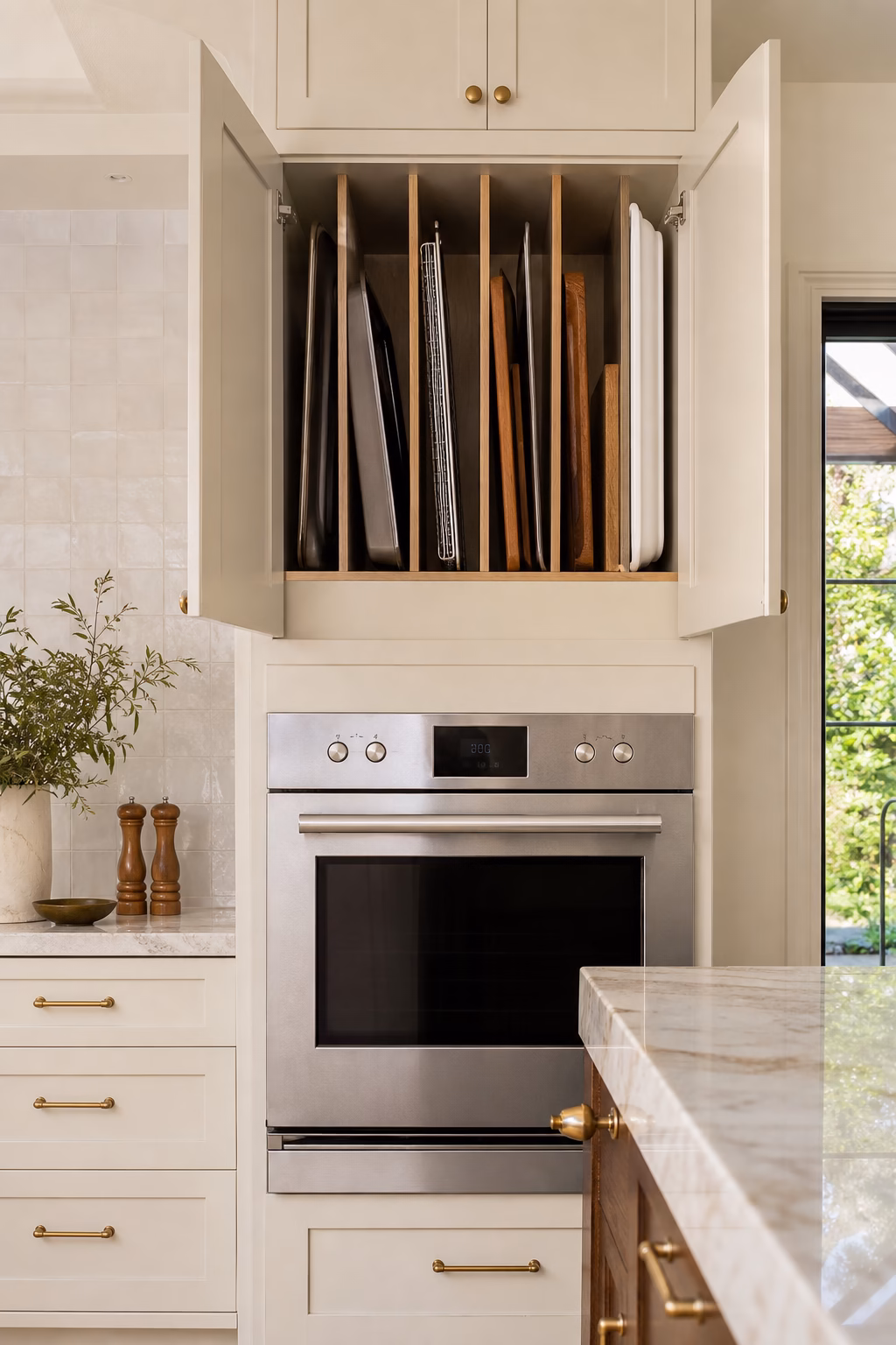 Kitchen cabinet with vertical tray dividers above the oven for baking sheets and boards.