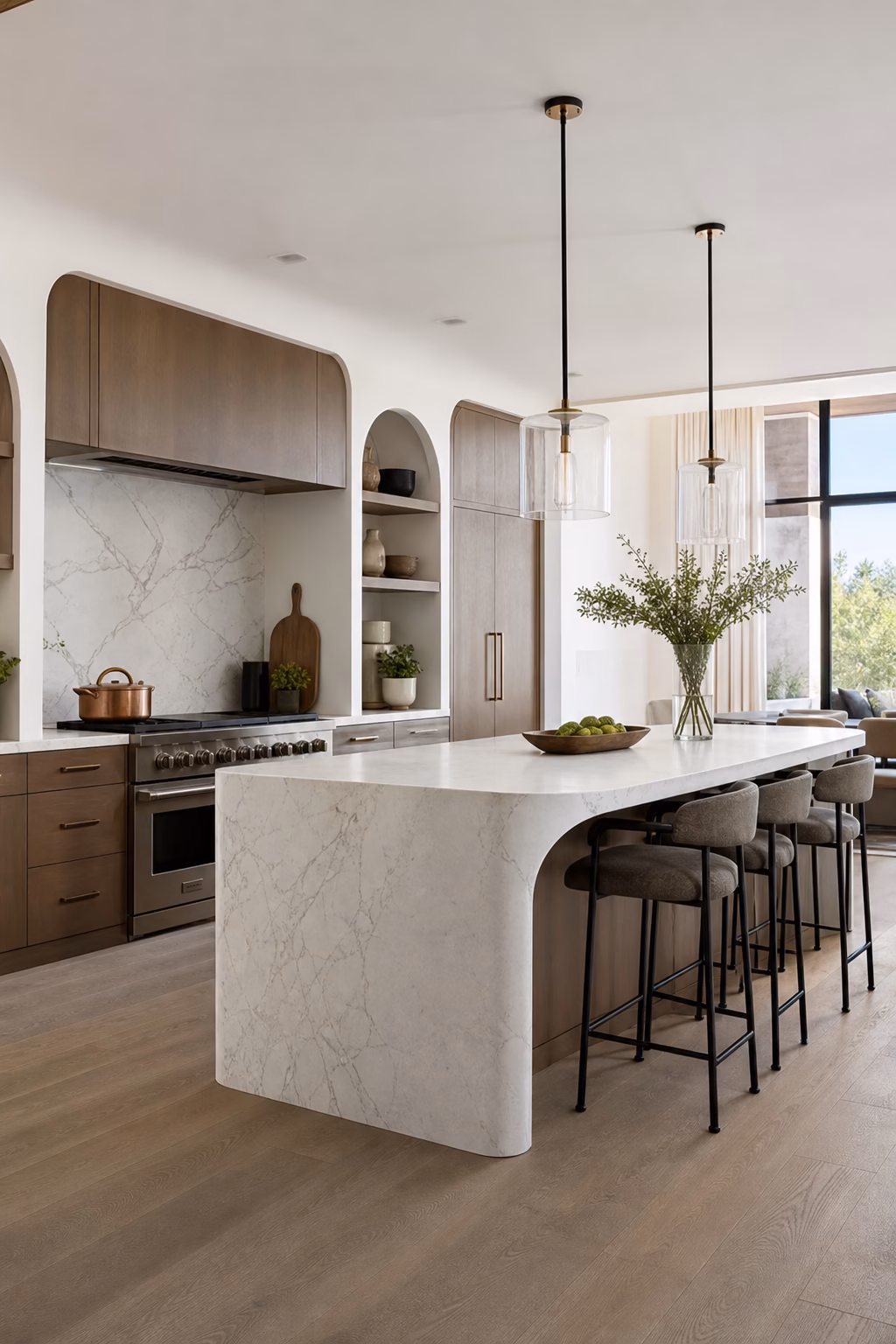 Open modern kitchen with a rounded island, arched niche, and soft sleek detailing.