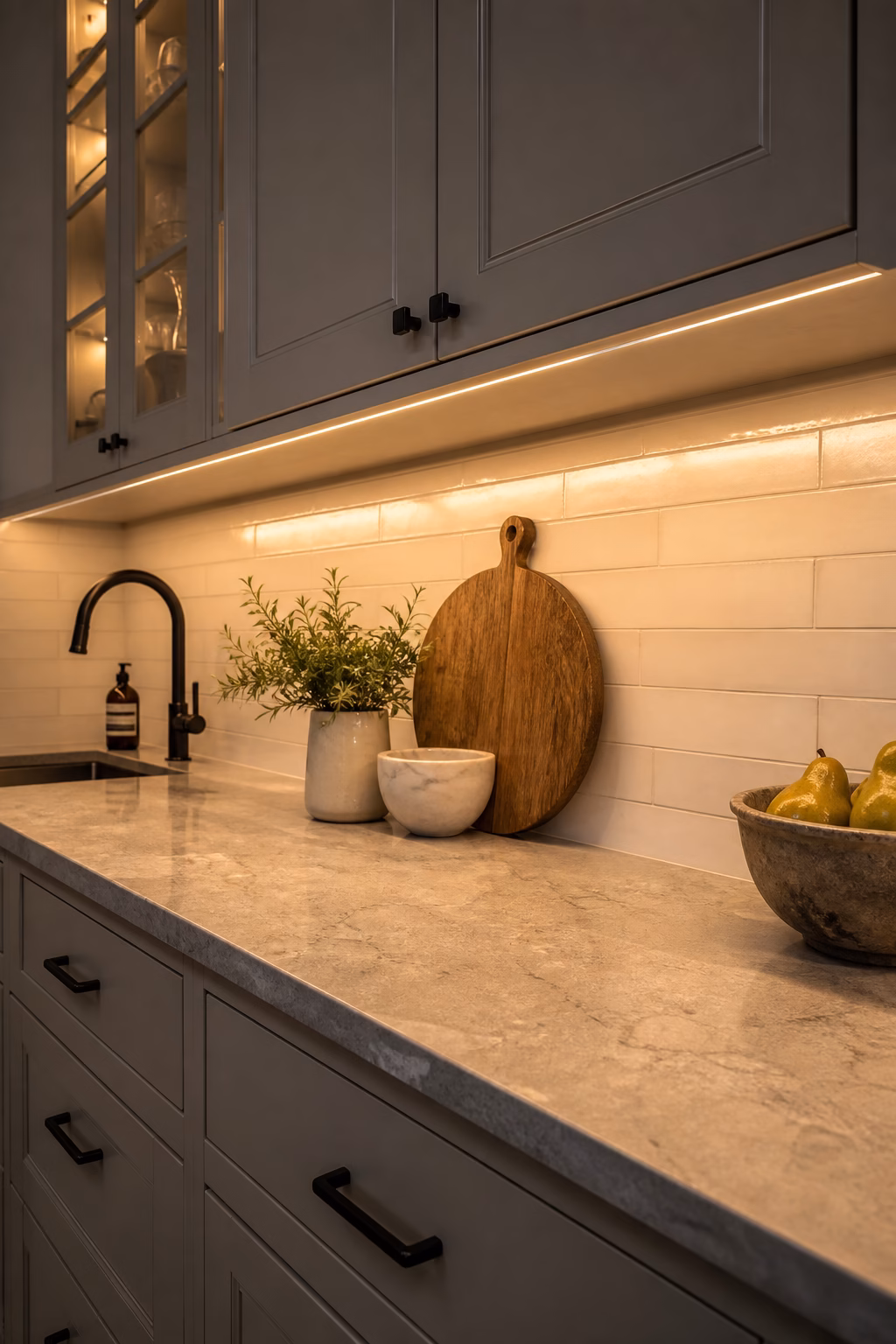 Kitchen backsplash and counter lit by warm under cabinet lighting