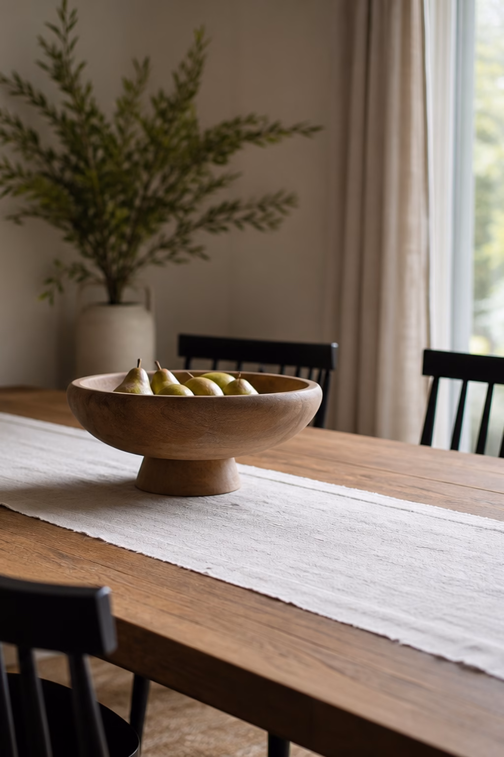 Wood pedestal bowl styled as a simple dining table centerpiece.