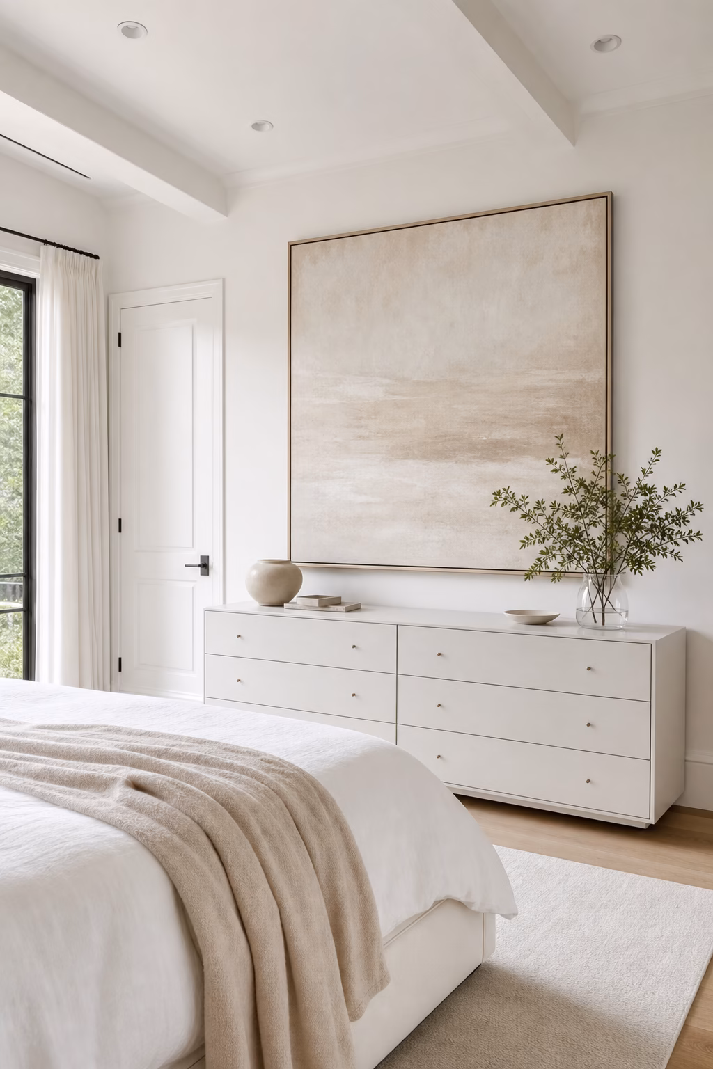 White bedroom with one large tonal abstract artwork, slim frame, and restful neutral styling.