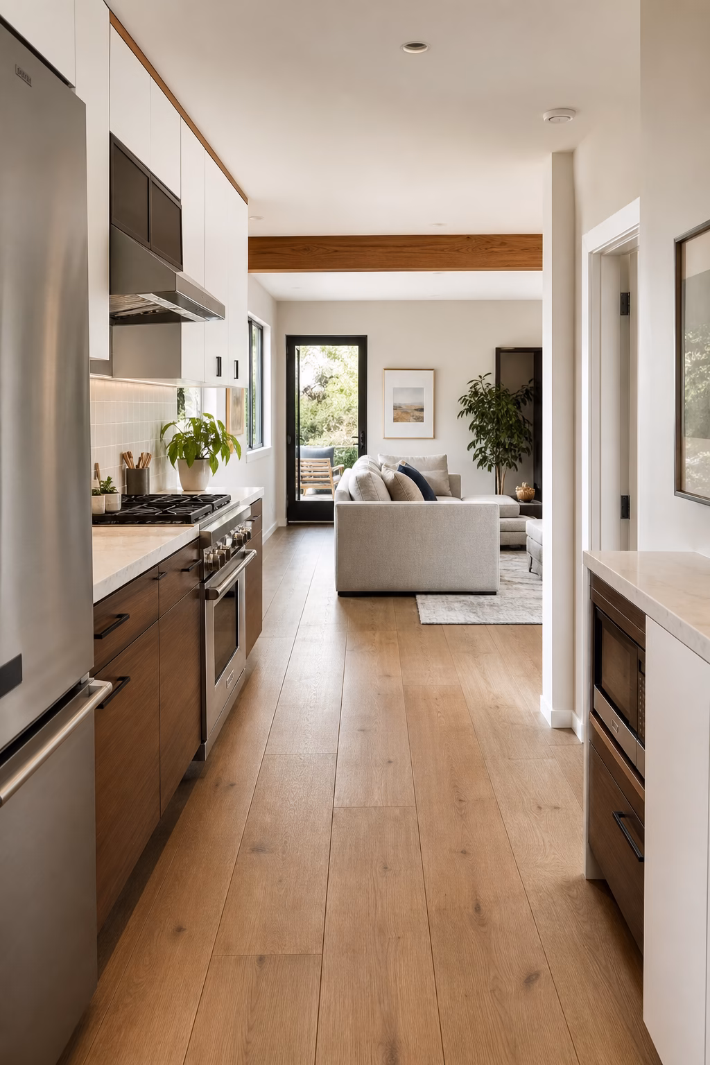 Open tiny kitchen with continuous wood flooring into the living area.