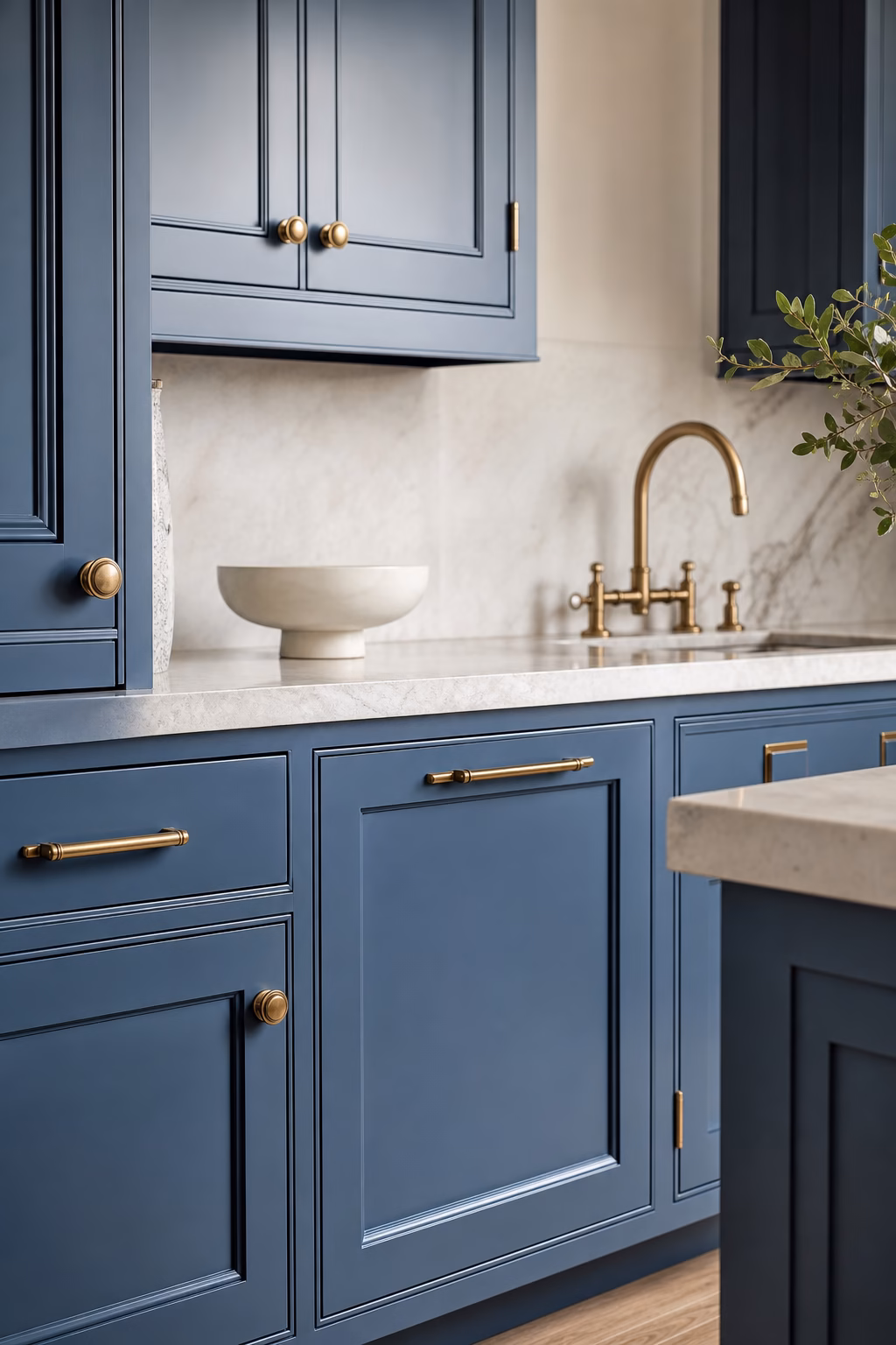 Refined blue kitchen with quiet aged brass hardware and pale stone counters.