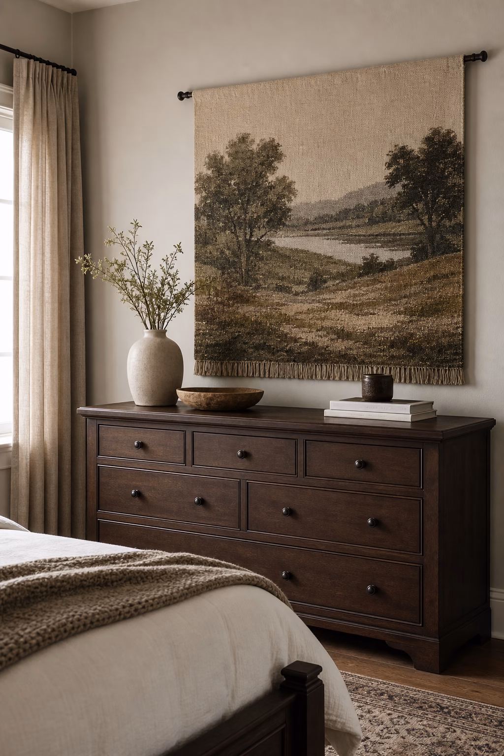 Muted woven landscape tapestry replacing framed art above a bedroom dresser.