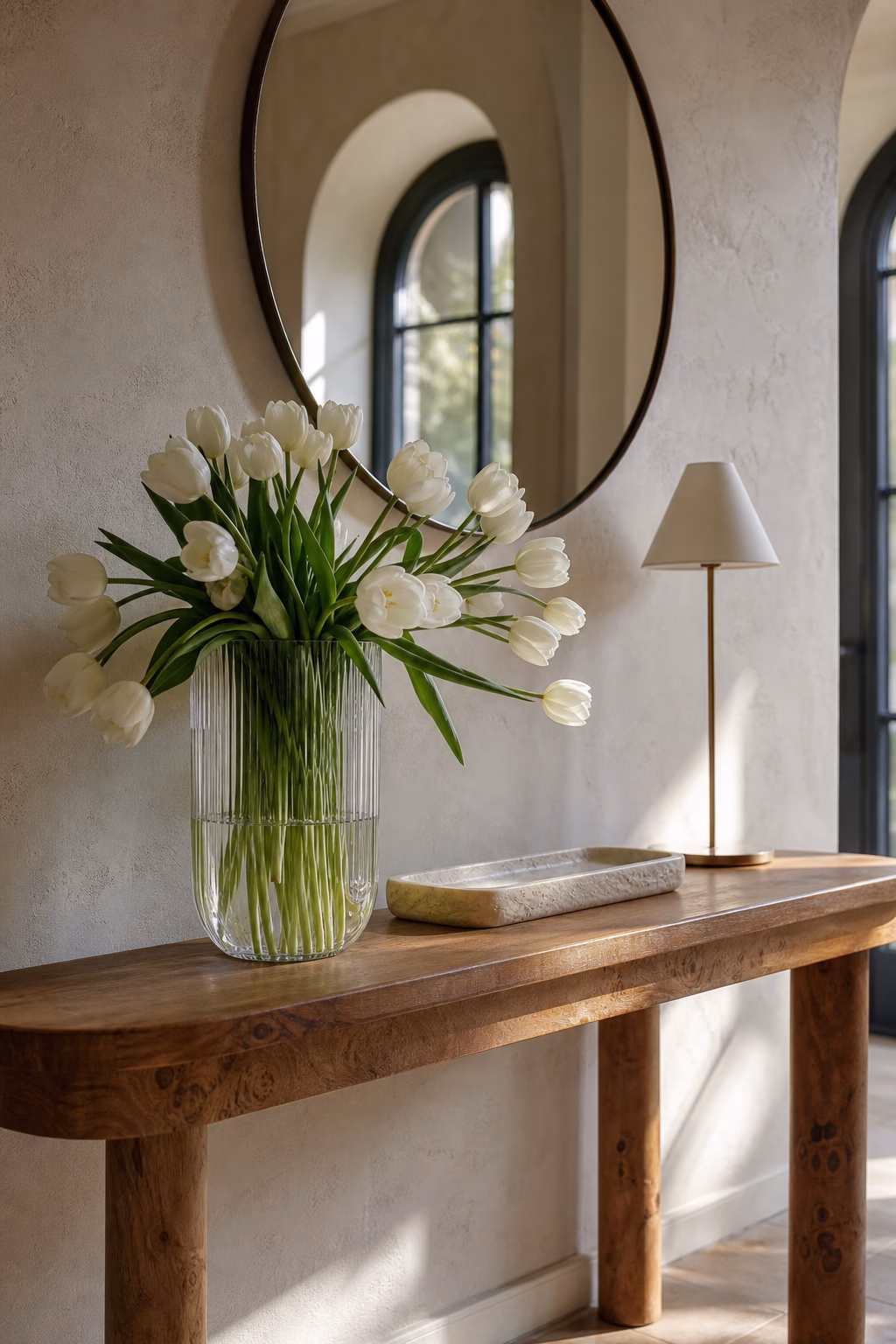 Ribbed glass vase with tulips on a sunny console table